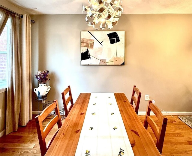 dining area featuring a chandelier, baseboards, and wood finished floors