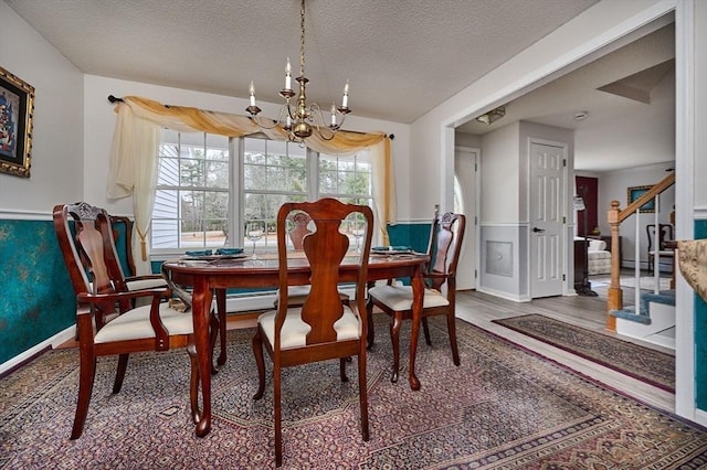 dining area featuring wood-type flooring, a notable chandelier, and a textured ceiling