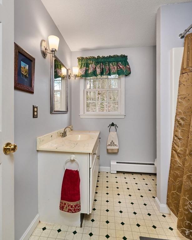 bathroom featuring vanity, a baseboard heating unit, and a textured ceiling