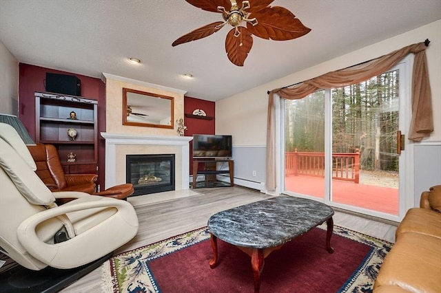 living room with a baseboard heating unit, hardwood / wood-style flooring, and ceiling fan