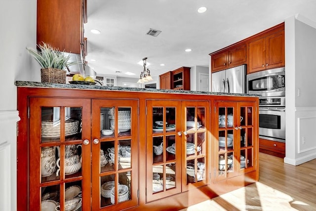 interior space featuring recessed lighting, visible vents, appliances with stainless steel finishes, light wood-type flooring, and glass insert cabinets