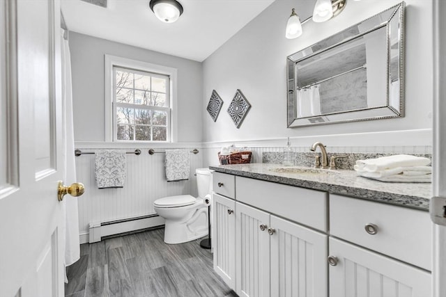 full bath with wainscoting, toilet, a baseboard radiator, wood finished floors, and vanity