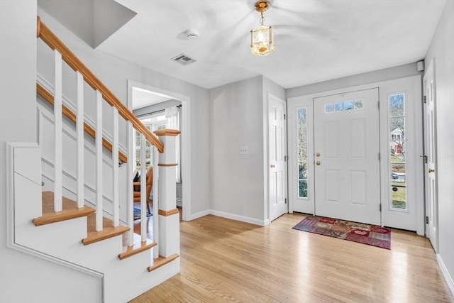 entrance foyer featuring stairs, visible vents, baseboards, and wood finished floors