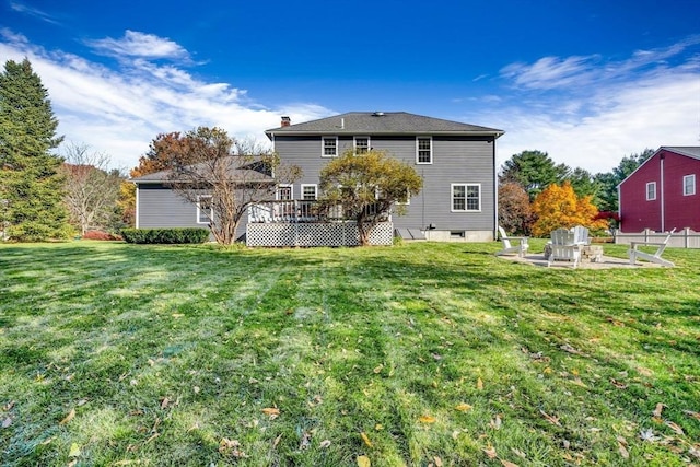 back of house featuring a patio area, a lawn, a chimney, and a wooden deck