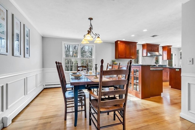 dining space featuring an inviting chandelier, light wood-style flooring, crown molding, and recessed lighting