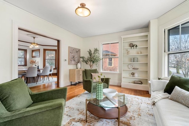 living area featuring a chandelier, light wood-style flooring, and baseboards