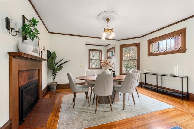 dining space with an inviting chandelier, ornamental molding, baseboards, and wood finished floors