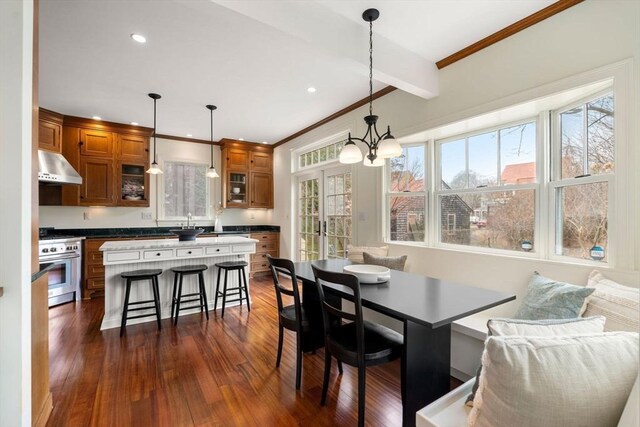 dining room with beamed ceiling, dark wood-type flooring, ornamental molding, recessed lighting, and an inviting chandelier