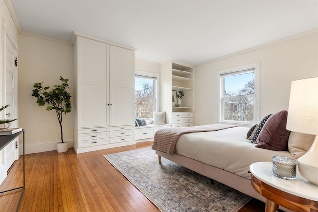 bedroom featuring light wood finished floors, multiple windows, baseboards, and ornamental molding