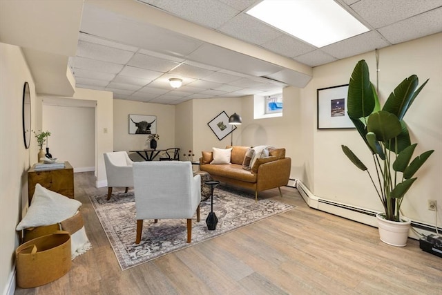 living area with wood finished floors, baseboards, baseboard heating, and a paneled ceiling