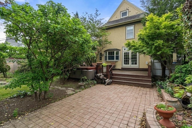 back of property with french doors, a patio area, a deck, and a hot tub