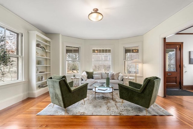 living area with a healthy amount of sunlight, light wood-style floors, and baseboards