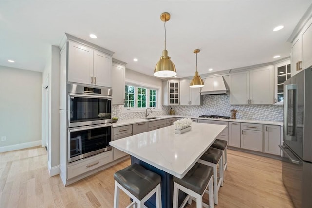 43 Lake Ave, Sharon, MA 02067 - kitchen featuring stainless steel appliances, custom range hood, decorative backsplash, a center island, and gray cabinets
