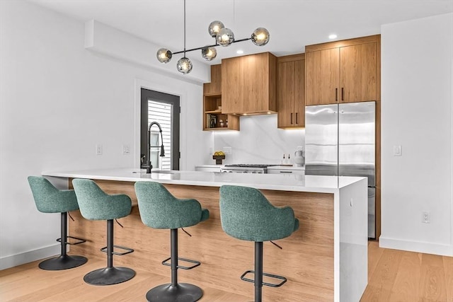 kitchen with stainless steel fridge, a breakfast bar area, brown cabinetry, and a sink