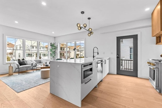 kitchen with a peninsula, light wood-style flooring, appliances with stainless steel finishes, and a sink