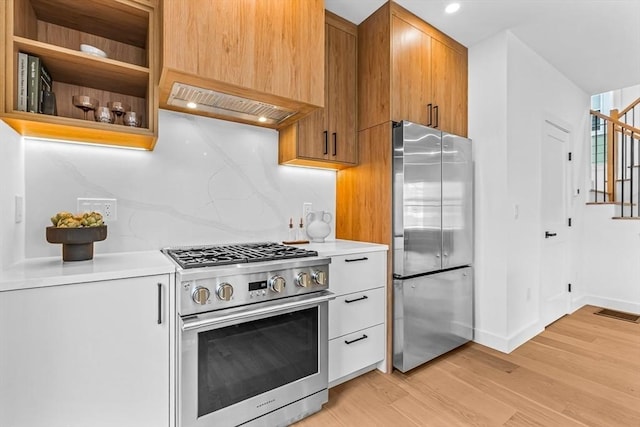 kitchen featuring light wood-style flooring, custom range hood, stainless steel appliances, light countertops, and backsplash