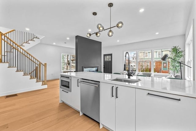 kitchen with light wood finished floors, light countertops, visible vents, open floor plan, and dishwasher