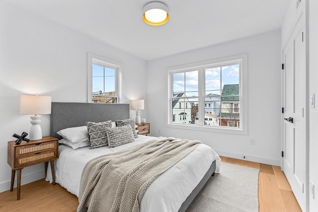 bedroom featuring light wood finished floors, multiple windows, and baseboards