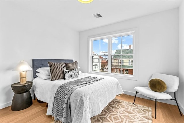 bedroom with visible vents, baseboards, and wood finished floors