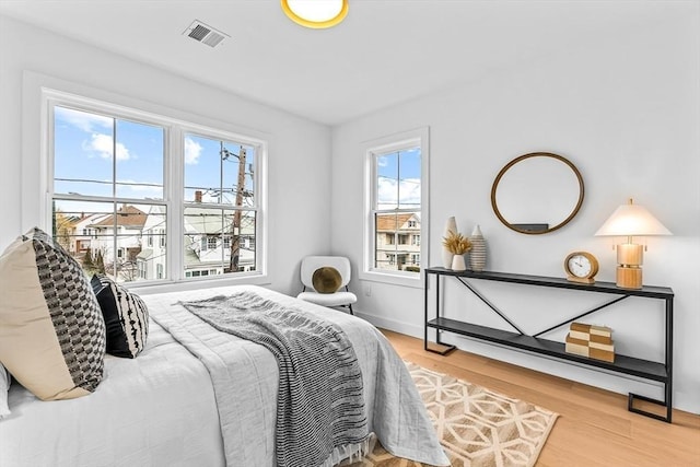 bedroom featuring visible vents, baseboards, and wood finished floors