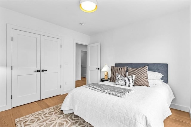 bedroom with a closet, baseboards, and wood finished floors