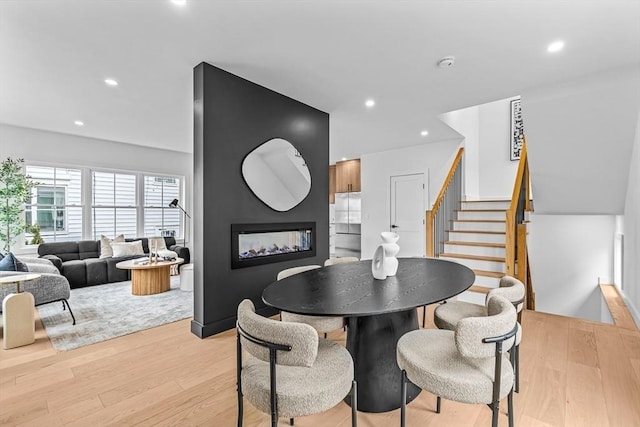 dining area with light wood-style floors, recessed lighting, a multi sided fireplace, and stairs