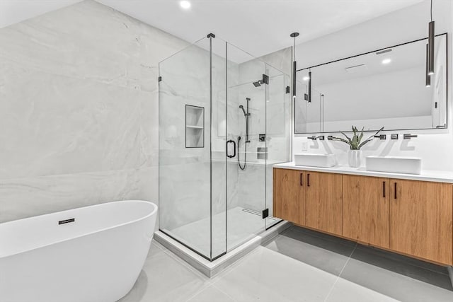 bathroom with tile walls, a marble finish shower, double vanity, tile patterned flooring, and a freestanding tub