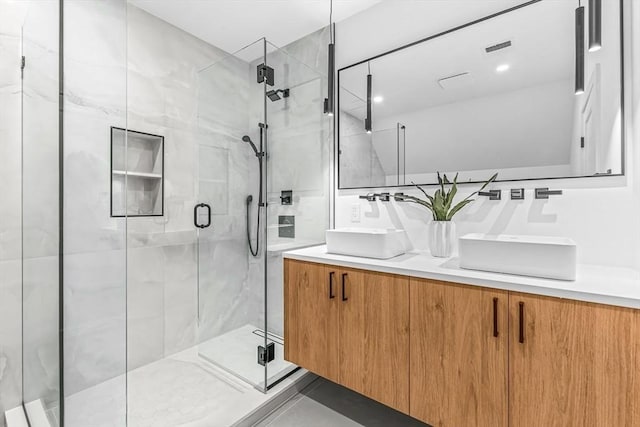 bathroom featuring a sink, a shower stall, and double vanity