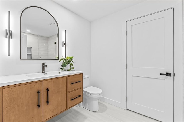 bathroom featuring a shower, vanity, toilet, and baseboards