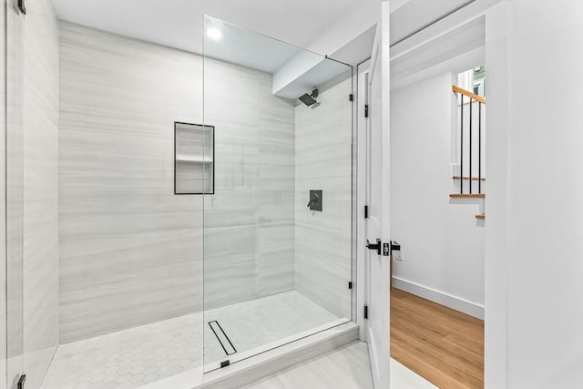 bathroom with a shower stall, baseboards, and wood finished floors