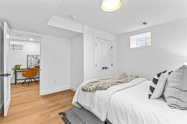 bedroom featuring a closet, visible vents, light wood-style flooring, and baseboards