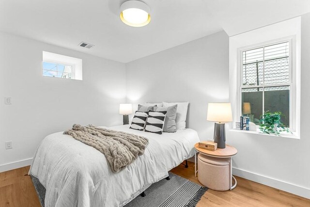 bedroom featuring baseboards, visible vents, and wood finished floors