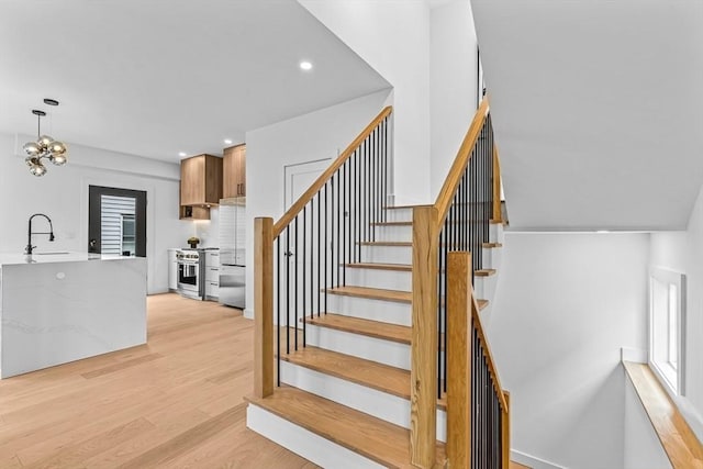 stairway featuring recessed lighting, an inviting chandelier, and wood finished floors