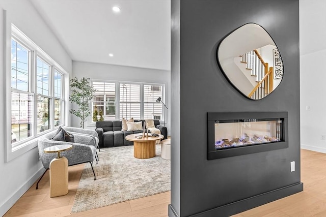 interior space featuring recessed lighting, baseboards, a multi sided fireplace, and wood finished floors