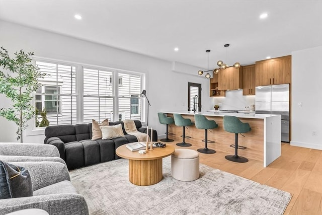 living area featuring baseboards, light wood finished floors, and recessed lighting