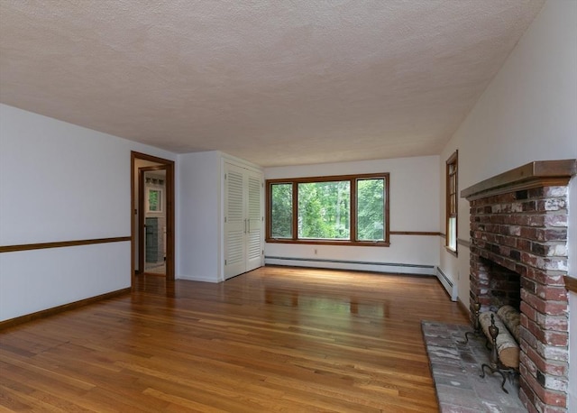 10 Whipple Rd, Hamilton, MA 01982 - unfurnished living room featuring a baseboard heating unit, light wood-type flooring, a fireplace, baseboards, and a textured ceiling