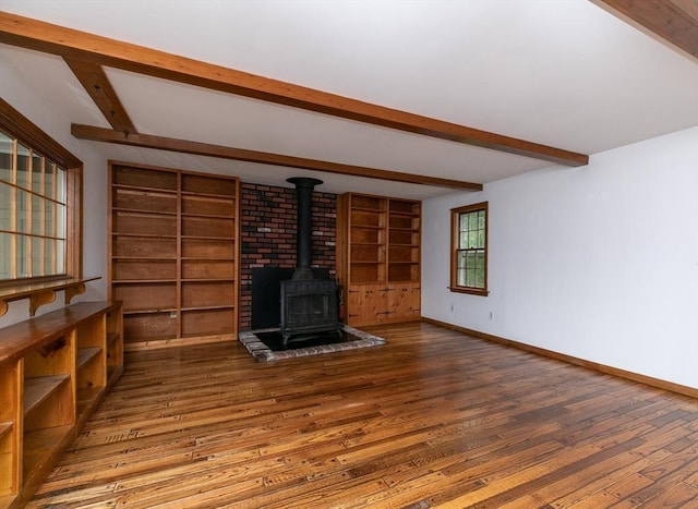 10 Whipple Rd, Hamilton, MA 01982 - unfurnished living room with beam ceiling, a wood stove, hardwood / wood-style flooring, baseboards, and built in shelves