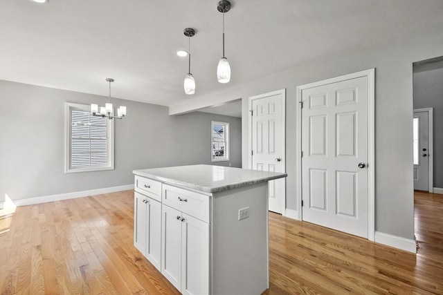119 Tripp St, Fall River, MA 02724 - kitchen featuring white cabinetry, a center island, light wood-type flooring, decorative light fixtures, and a chandelier