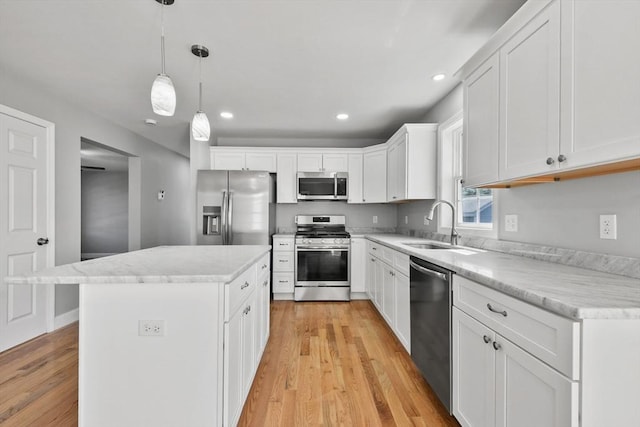 119 Tripp St, Fall River, MA 02724 - kitchen featuring appliances with stainless steel finishes, light wood-style flooring, a center island, white cabinetry, and light countertops