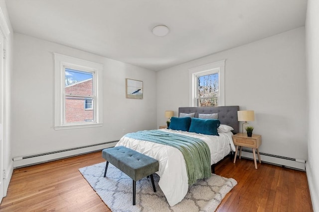 bedroom featuring multiple windows, a baseboard radiator, and wood-type flooring