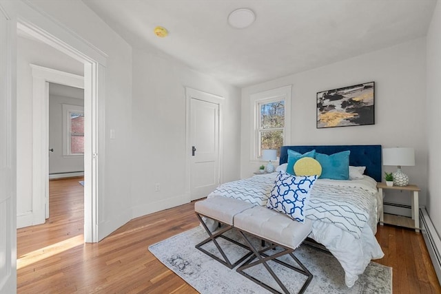 bedroom featuring wood-type flooring and a baseboard heating unit