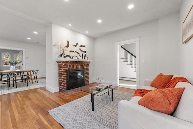 living room featuring a fireplace, wood-type flooring, and baseboard heating