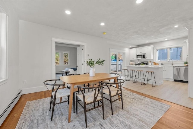 dining area featuring light hardwood / wood-style floors, baseboard heating, and sink