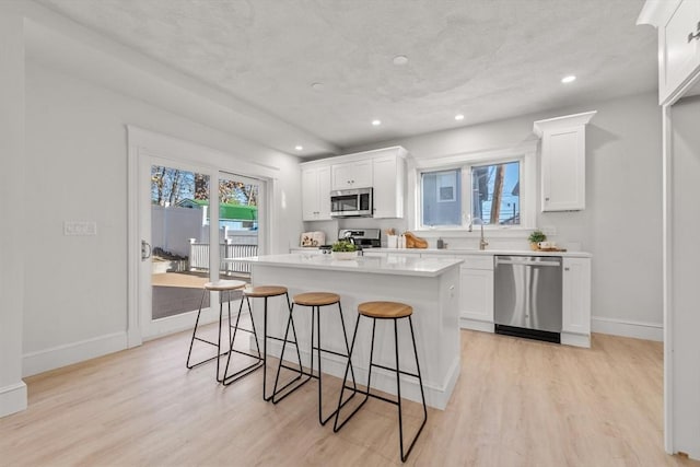 kitchen with white cabinets, light wood-type flooring, and appliances with stainless steel finishes