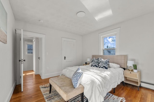 bedroom featuring wood-type flooring and a baseboard radiator