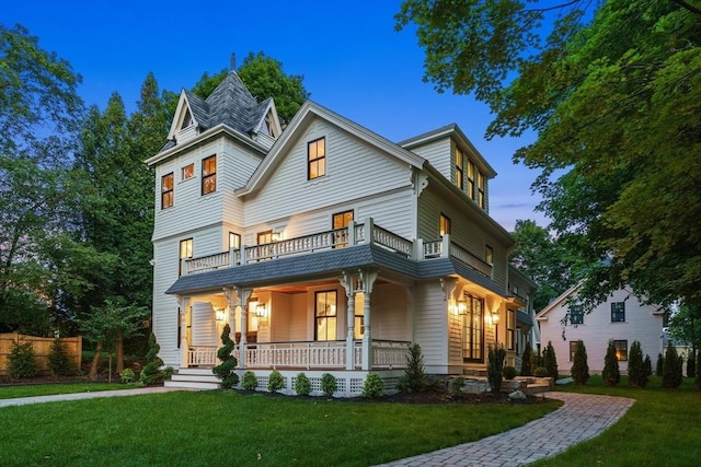 view of front of home with a balcony, a yard, and covered porch