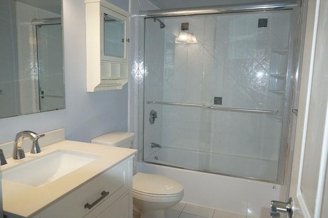 full bathroom with combined bath / shower with glass door, tile patterned floors, vanity, and toilet