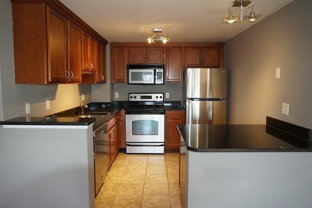 kitchen featuring sink, stainless steel appliances, kitchen peninsula, dark stone counters, and light tile patterned floors