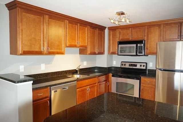 kitchen featuring sink, appliances with stainless steel finishes, and dark stone counters