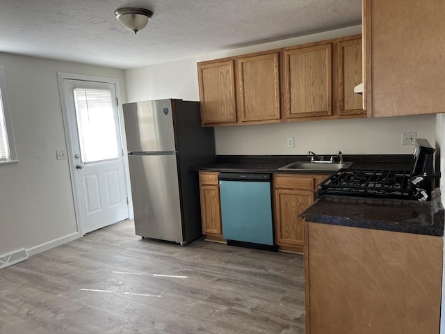 kitchen with visible vents, light wood-style flooring, freestanding refrigerator, a sink, and dishwashing machine